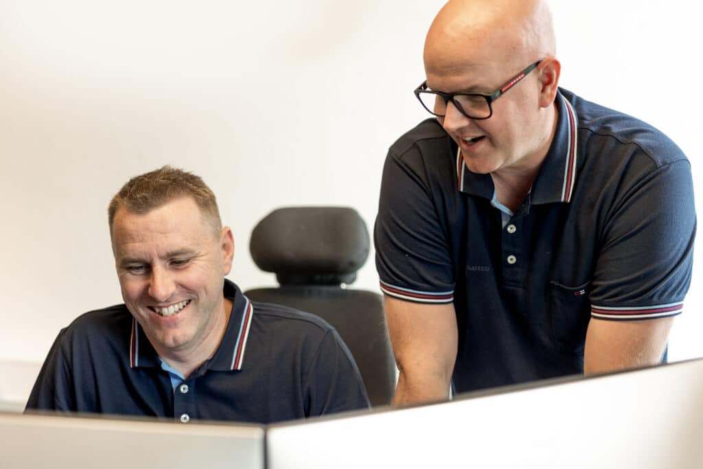 To kollegaer tjekker godkendt regnskabsprogram på en stationær computer.